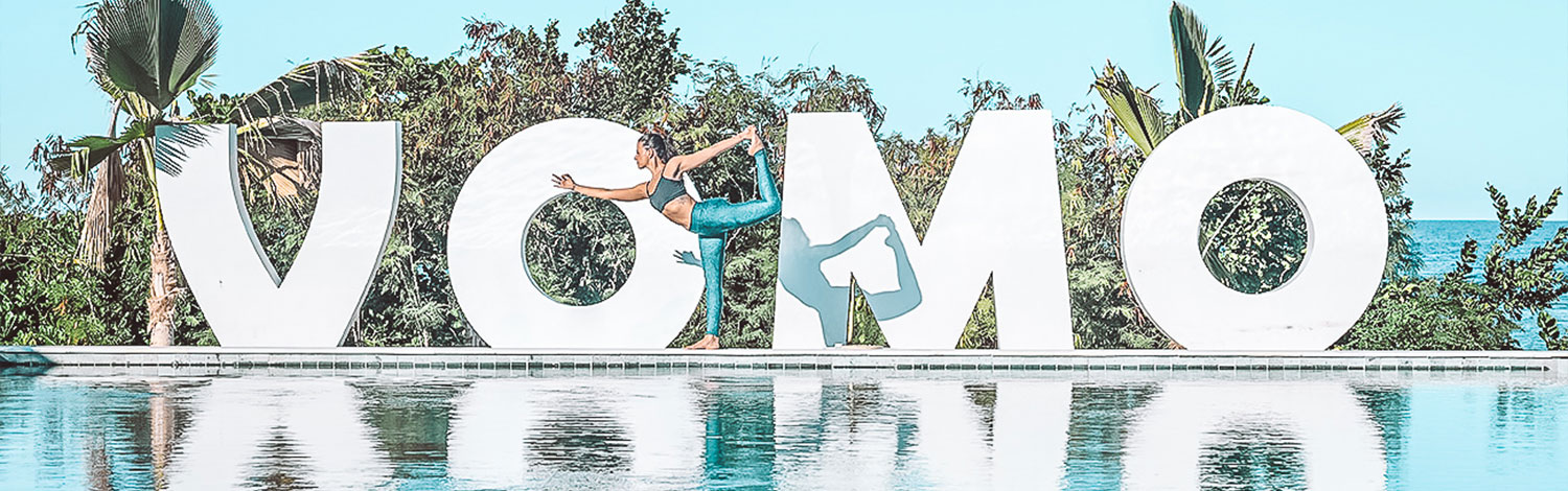 Yoga teacher on vomo island fiji vivi on front of vomo rocks pool sign